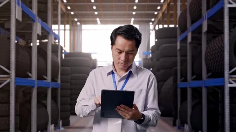 Asian Male Worker Is Working With A Tablet at Tire Warehouse Stock Footage 341786133