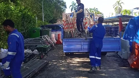 Asian Male Workers Load Plastic Road Barriers and Traffic Controls onto Trucks Stock Footage 309306837