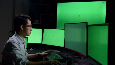 Asian Male Working On Computer With Multiple Chroma Key, Green Screen Displays Stock Footage 157190288