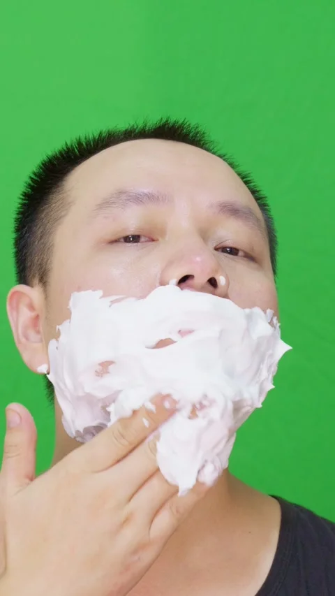 Asian man applying white shaving cream on his face ready to shave Stock Footage 315418124