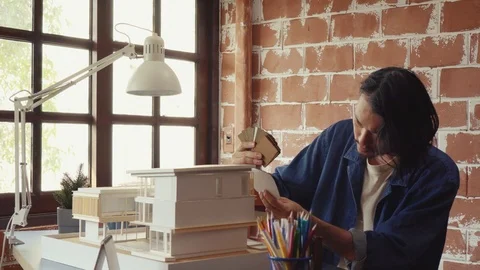 Asian man architecture/designer selecting wall color for model house/home Stock Footage 111679820
