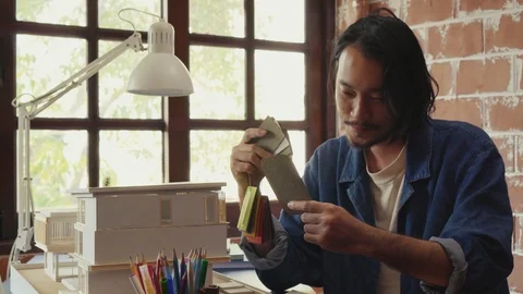 Asian man architecture/designer selecting wall color for model house/home Stock Footage 111679916