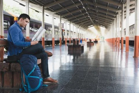 Asian man with backpack sitting on platform at train station. backpacker or t Stock-Fotos