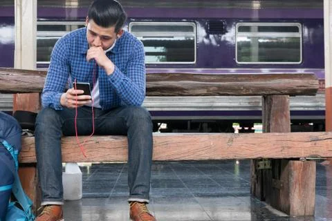 Asian man with backpack sitting on platform at train station. backpacker or t Stock-Fotos