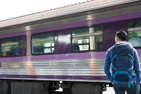 Asian man with backpack standing on platform at train station. backpacker or  Stock Photos
