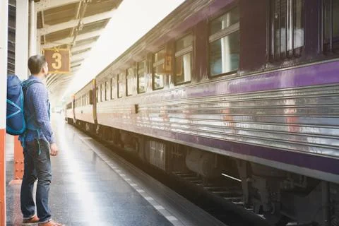 Asian man with backpack standing on platform at train station. backpacker or  Stock Photos