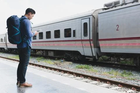 Asian man with backpack standing on platform at train station. backpacker or  Foto stock