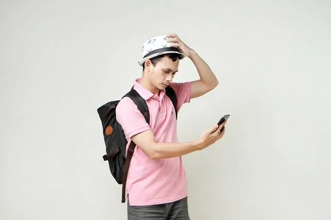 Asian man backpacker hold mobile phone with confused expression. travelling.. Stock Photos