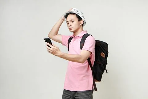 Asian man backpacker hold mobile phone with confused expression. travelling.. Stock Photos