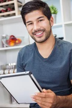 Asian man with beard using tablet computer in kitchen Stock Photos