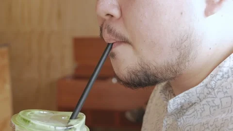 Asian man with beard while drinking coffee or juice with straw in cafe in summer 動画素材 293924701