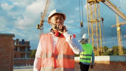 Asian man builder engineer worker in hard hat with use a walkie-talkie on Stock Footage 139341643