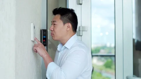 Asian man, calling rings the intercom of the house, pressing the button, waiting Stock Footage 218233418