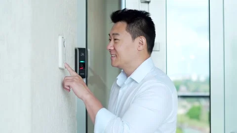 Asian man, calling rings the intercom of the house, pressing the button, waiting Stock Footage 218233500