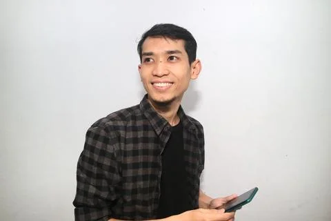 Asian Man with candid expression while looking at smartphone. Stock Photos
