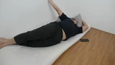 Asian man checking his phone directly after waking up on bed in the morning Stock Footage 296004408