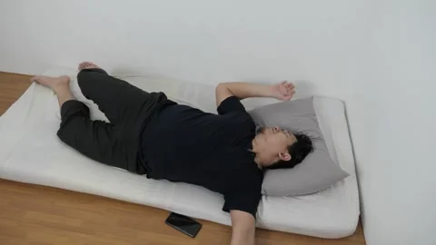 Asian man checking his phone directly after waking up on bed in the morning Stock Footage 296004480