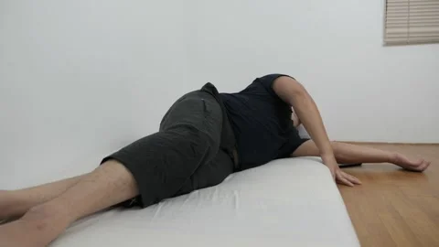 Asian man checking his phone directly after waking up on bed in the morning Stock Footage 296004482