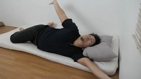 Asian man checking his phone directly after waking up on bed in the morning Stock Footage 296004483