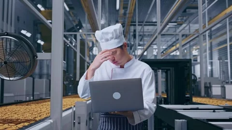 Asian Man Chef Using A Laptop And Having A Headache In Cookie Factory Stock Footage 318080758