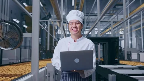 Asian Man Chef Using A Laptop And Smiling In Cookie Factory Vidéo 318080782