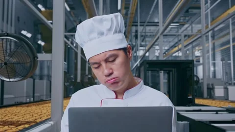 Asian Man Chef Using A Laptop And Having A Headache In Cookie Factory Stock Footage 318081619