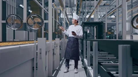 Asian Man Chef Using Smartphone And Pointing To Side In Cookie Factory Vidéo 318082462