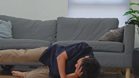 Asian man collapses holding head in intense pain during vertigo or migraine Stock Footage 335908360