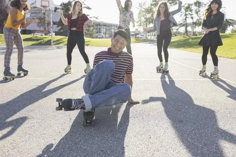 Asian man demonstrating dance on rollerskates to friend Stock Photos