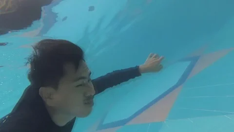 Asian man diving in swimming pool, Stock Footage 70788366