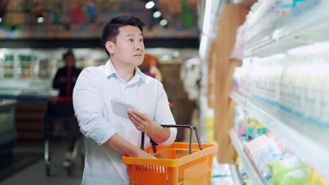 Asian man doing daily shopping in grocery store in the supermarket uses a checkl Stock Footage 199846992