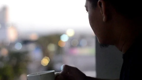 Asian man drinking coffee until empty. City view from the hotel balcony Stock Footage 97022515