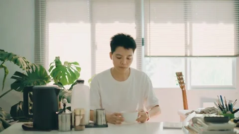 Asian man drinking coffee while working from home at home office in the morning Stock Footage 247987758