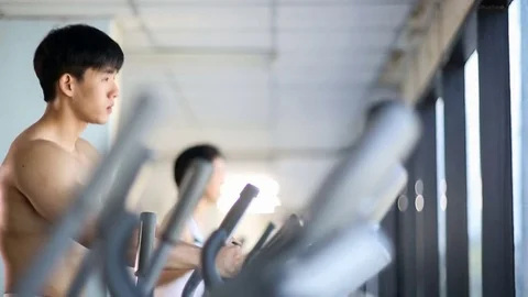 Asian man exercise on elliptical trainer machine Stock Footage 70612326