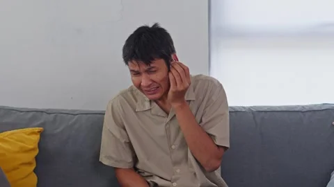 Asian man experiencing sudden ear pain or hearing loss looking distressed on Видео 332712450