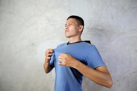 Asian man expression of being hot because of the tropical weather Stock Photos