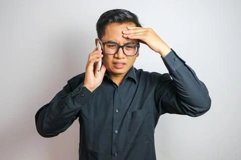 Asian man feeling dizzy while receiving a call wearing casual clothes isola.. Stock Photos