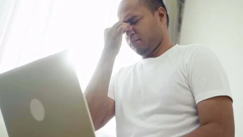 Asian man feeling stress from sickness and he try to work at home but he get hur 库存影片 135294792