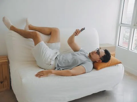 Asian man focus on the phone while relaxed on the sofa. Stock Photos