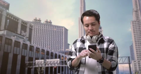 Asian Man Freelancer With Headphones Using Smartphone While Standing In Front Stock Footage 245288406