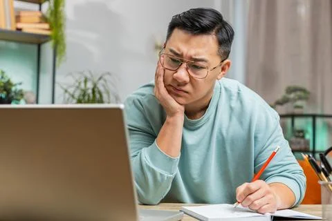 Asian man freelancer making notes on notebook at home, use laptop, prepare Stock Photos