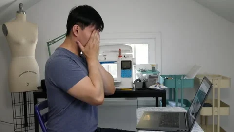 Asian man getting tired from working on his laptop in his craftroom Stock Footage 247874279