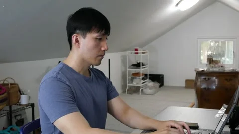 Asian man having a stretch break while working on his laptop Stock Footage 247874233