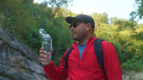 Asian man hiker  taking a break to drink from a rock within the national park. Video stock 342409823