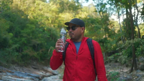 Asian man hiker  taking a break to drink from a rock within the national park. Video stock 342409926