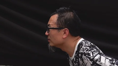 An Asian man is hit in the face with a large exploding water balloon in Stock Footage 113757260