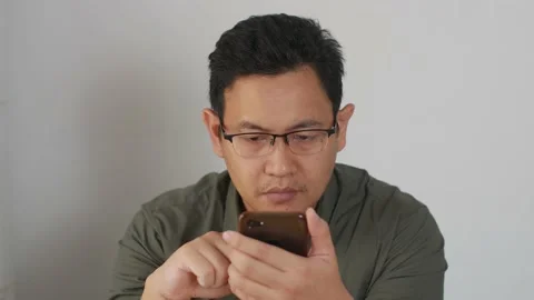 Asian man holding and using smart mobile phone, scrolling browsing internet o Stock Footage 141612079