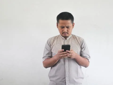 Asian man holding his mobile phone with serious expression Stock Photos