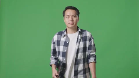 Asian Man Holding Tablet While Walking On Green Screen In The Studio Stock Footage 248006173