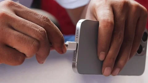 Asian man inserting a USB-C connector into a modern smartphone Stock Footage 347114450